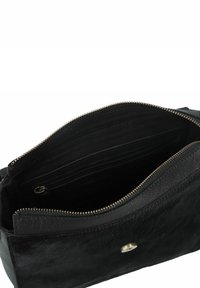 Zwarte leren handtas met een ritssluitingen bovenkant, voorzien van een gestructureerde afwerking, ruime interieur en details in goudkleur.