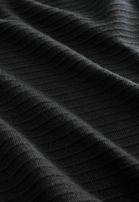 Schwarzer, strukturierter Stoff mit einem gerippten Muster, das Wellen und Falten zeigt und ein weiches, gewebtes Aussehen präsentiert. Geeignet für verschiedene textile Anwendungen.