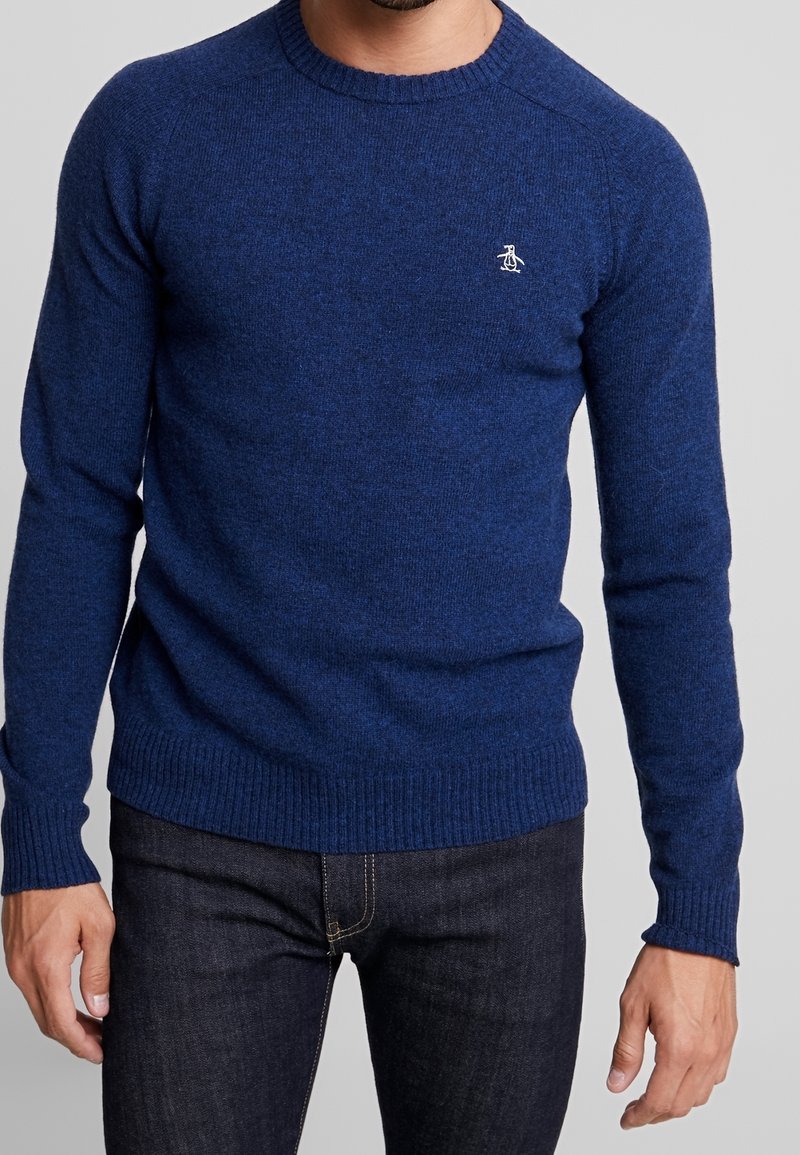 Navy blue crewneck sweater made of textured knit fabric with ribbed cuffs and hem; features a small white penguin logo on the chest.