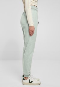 Ljusgröna joggers i mjukt tyg med elastiskt midjeband, sidofickor och dragsko. Matchas med vita sneakers med gröna detaljer.