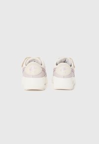 Les baskets Nike Air présentent un design violet clair et crème, avec une semelle texturée beige et un accent de talon rond. Conçues pour le confort et le style.