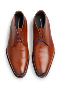 Chaussures habillées en cuir marron avec une finition lisse, une pointe pointue et des lacets bleus. Présente des coutures minimales et un design élégant.