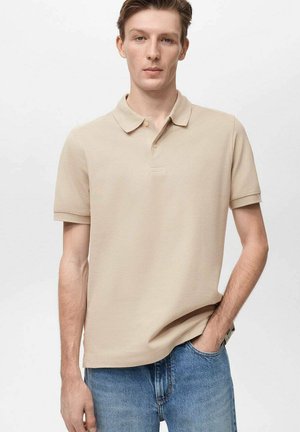 Polo de culoare bej cu mânecă scurtă și guler, având o textură netedă și închidere cu trei butoane. Asortat cu blugi din denim albastru deschis.