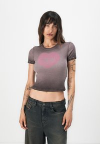 Gray cropped t-shirt with short sleeves, featuring a faded pink heart graphic. Soft texture and fitted design. Worn with dark, loose jeans.