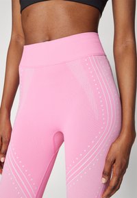Leggings fucsia a vita alta con una finitura testurizzata, caratterizzati da strisce bianche e motivi a pois sui lati per un dettaglio migliorato.