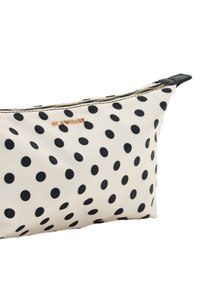 Sac de maquillage à pois crème, avec des pois noirs, une finition texturée, une fermeture éclair dorée et un accent en simili cuir noir sur un côté.