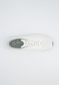 Weiße Sportschuhe mit einem strukturierten Mesh-Obermaterial, flachen Schnürsenkeln und einer grauen gepolsterten Innensohle. Abgerundete Zehenpartie mit einem schwarzen Akzent an der Sohle.