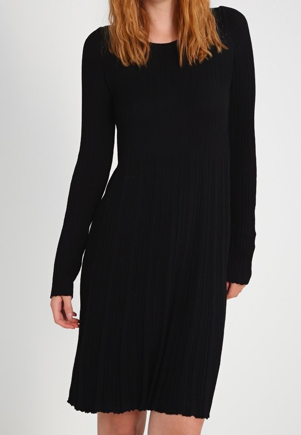 Svart ribbad stickad klänning med långa ärmar, rund halsringning och en utsvängd fåll. Texturen verkar mjuk och strukturerad, vilket betonar vertikala linjer.