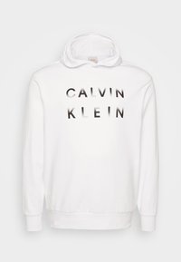 Biała bluza z kapturem z dużym gradientowym czarnym napisem "CALVIN KLEIN" na przodzie. Miękka tkanina, kieszeń kangurza i ściągacze przy mankietach.