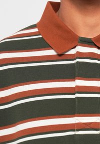Gestreept poloshirt met groene, rode en witte strepen, voorzien van een bruine kraag en een gestructureerde stof voor een stevige uitstraling.