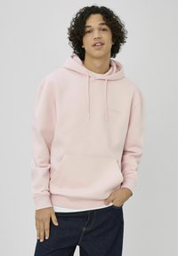 Sweat à capuche rose clair en mélange de coton doux. Comprend une poche kangourou devant, une capuche avec cordon de serrage, et des poignets et ourlet côtelés.