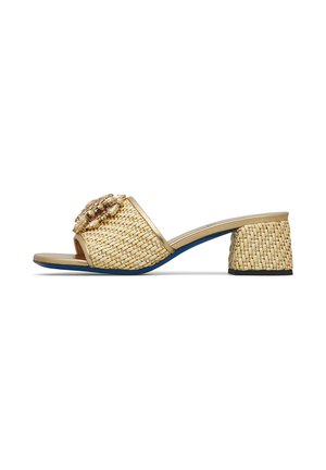 Mule beige intrecciato con punta aperta, tacco a blocco e decorazione gioiello color oro sulla larga fascia frontale, suola blu navy visibile lateralmente.