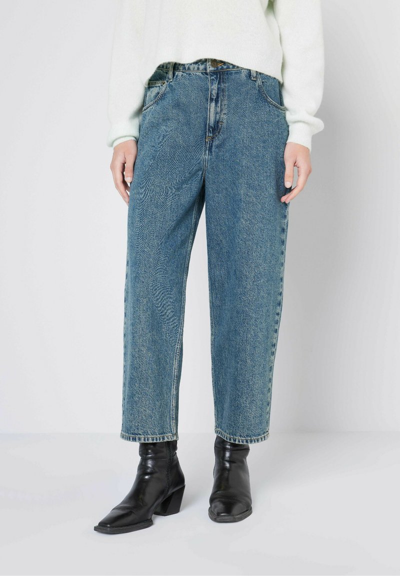 Lichtblauwe denim jeans met een relaxed fit, met een hoge taille, subtiele vervaging en een klassiek vijf-pocket ontwerp, gecombineerd met zwarte enkellaarsjes.