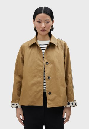 Giacca leggera marrone con design a colletto, bottoni neri e maniche a righe con dettagli a pois. Texture liscia, vestibilità comoda.