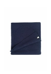 Dunkelblauer gestrickter Schal, gefaltet zu einem Quadrat, mit einem kleinen schwarz-weißen Stoffetikett in einer Ecke, auf einem weißen Hintergrund.