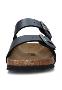 Zwarte leren slipper met twee verstelbare banden, zilveren gespen en een gevormde kurken voetbed. Getextureerde zool voor grip.