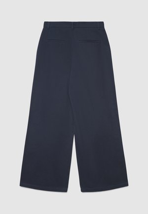 Pantalon large bleu marine à texture lisse, doté d'une ceinture plate et de deux poches arrière. Le design est minimaliste et ajusté.