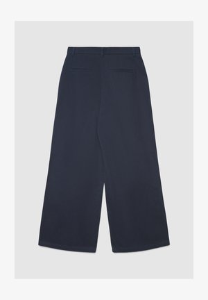 Pantalon large bleu marine à texture lisse, doté d'une ceinture plate et de deux poches arrière. Le design est minimaliste et ajusté.