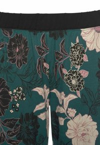 Floral leggings featuring a dark teal background with black, pink, and white flowers. Elastic black waistband, soft fabric texture.