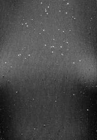 Tejido negro con una textura suave, con manchas blancas dispersas que se asemejan a estrellas, creando un patrón sutil en la superficie.