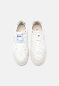 Λευκά δερμάτινα αθλητικά παπούτσια με γαλάζιες λεπτομέρειες, διάτρητη μυτερή μύτη, στρογγυλά κορδόνια και υφασμένο γκρι τμήμα από καστόρι στη φτέρνα. Λεπτομέρειες σε χρυσό μέταλλο.