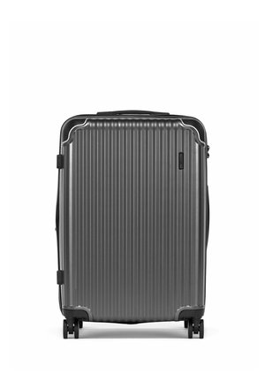 Szara walizka z twardą skorupą, z pionowymi żebrowaniami, czterema kółkami i górnym uchwytem, stojąca pionowo na białym tle.