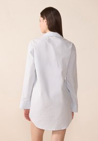 Abito camicia a maniche lunghe, a righe blu chiaro, con colletto, taglio dritto e polsini. Tessuto morbido e dettaglio dell'orlo curvo.