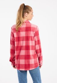 Camicia in flanella a quadretti rossi e rosa con maniche lunghe e colletto, caratterizzata da una vestibilità comoda e polsini abbottonati; trama morbida.