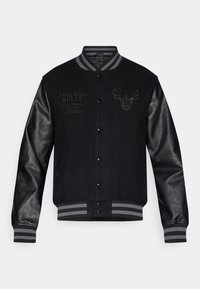 Casaco varsity preto com mangas de couro cinza, apresentando o logótipo e lettering dos Chicago Bulls. Colarinho e punhos canelados com detalhes listrados.