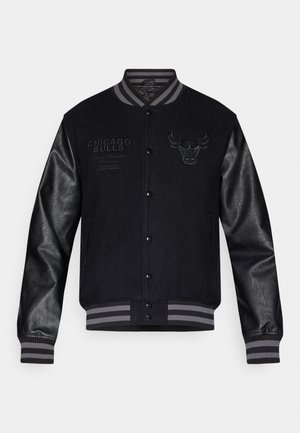 Črna jakna s kapuco iz varsity sloga z sivimi usnjenimi rokavi, s logotipom Chicago Bulls in napisi. Srajčni ovratnik in manšete s črtastimi akcenti.
