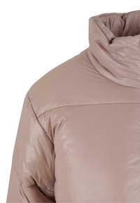 Lyserosa pufferjakke med høy krage, blank tekstur og quiltet design. Stoffet ser jevnt og isolert ut.