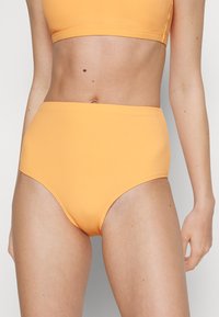 Hochgeschnittene Bikinihose aus geripptem Material in leuchtendem Orange, mit nahtlosem Design und klaren Linien für eine figurschmeichelnde Silhouette.
