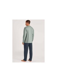 Heren loungewear set met een lichtgroene longsleeve top en marineblauwe geblokte broek, gemaakt van een zachte stof en met een ontspannen pasvorm.