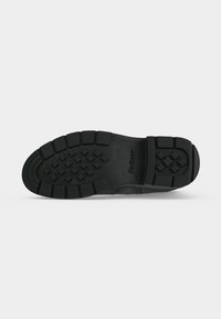 Semelle de chaussure en caoutchouc noir avec des motifs sur la bande de roulement et le nom de la marque Barbour embossé près du talon.