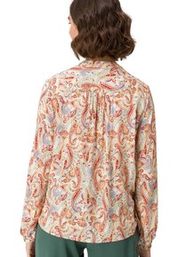 Blusa de manga larga en crema con un colorido patrón paisley. Presenta un detalle de espalda fruncida y una tela suave con un ajuste relajado.