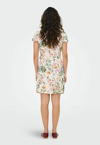 Vestido corto de tejido ligero con estampado floral, cintura ajustada, mangas tipo farol y dobladillo por encima de la rodilla. Llevado con zapatos tipo slip-on marrones.