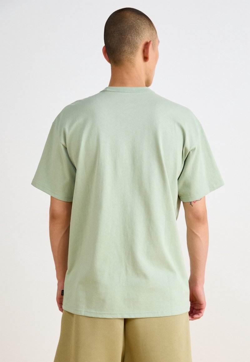 Světle zelené bavlněné tričko s krátkým rukávem a kulatým výstřihem. Hladká textura, uvolněný střih, bez viditelných vzorů nebo grafik.