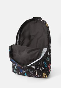 Sac à dos noir avec un design graphique coloré mettant en vedette des logos et des formes abstraites. Le compartiment principal a un intérieur lisse et doublé. Fermeture zippée.