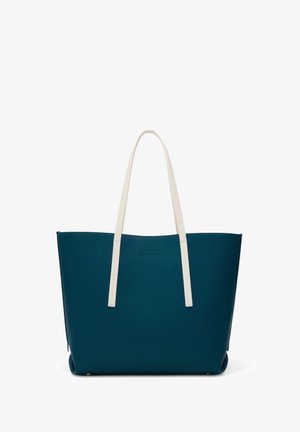 Bolso tote de color verde petróleo oscuro con largas asas blancas para el hombro, forma estructurada y un discreto logotipo en relieve en la parte frontal, mostrado sobre un fondo blanco.