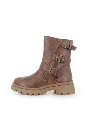 Bota de cuero marrón hasta el tobillo con dos hebillas ajustables, un acabado texturizado y una suela de goma gruesa. Detalle de costura lateral visible.