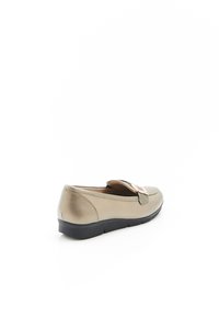 Mocassin en cuir beige avec une finition brillante, doté d'une bande décorative et d'une semelle en caoutchouc noire. Conçu pour un enfilage facile.