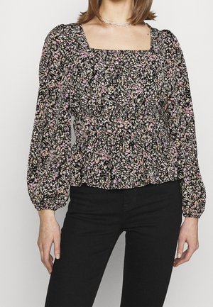 Blusa nera floreale a maniche lunghe con scollatura quadrata, vita arricciata e vivaci motivi floreali in rosa e giallo su uno sfondo scuro.