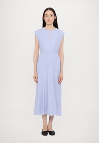 Rochie lavandă, până la genunchi, cu mâneci scurte, o decupare subtilă la gât și un corset ajustat care se continuă cu o fustă fluidă. Pur și simplu cu balerini negri.