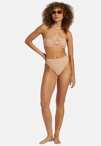 Set bikini a righe in rosa, giallo e verde; top bandeau con fibra al centro e parte inferiore a vita alta. Tessuto morbido, hardware ridotto.