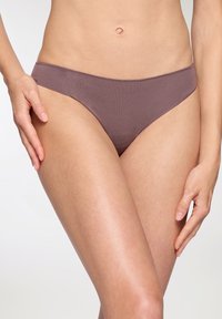 Slip bikini in un morbido colore mauve, realizzato in tessuto morbido con una superficie liscia e un design minimalista. Presenta aperture per le gambe a taglio alto.