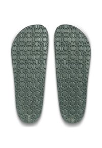 Semelles en caoutchouc gris avec un motif en forme de nid d'abeille, présentant une surface texturée pour une meilleure adhérence et un soutien optimal. Conçues pour le confort et l'alignement du pied.