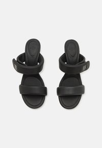 Zwarte schuifsandalen gemaakt van soepel synthetisch materiaal, met twee brede banden en een gewatteerde voetbed. Inclusief een klein logoaccent.