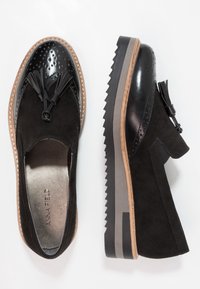 Černé kožené a semišové boty s robustní podrážkou, zdobené perforovanými detaily a třásněmi. Nazouvací design s elastickými stranami.