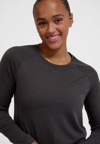 Dunkelgraues Langarmshirt mit Rundhalsausschnitt, das einen strukturierten Stoff und ein kleines "hummel"-Logo auf der Brust hat.