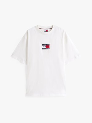 Camiseta de algodón blanca con cuello redondo, que presenta un colorido parche del logo de Tommy Hilfiger en el pecho. Tiene mangas cortas y un ajuste relajado.